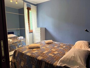 Un dormitorio con cama, cómoda, espejo y ventana con cortinas.