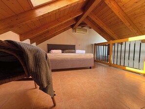 A bedroom with a sloped ceiling, a bed, a wooden railing, and a view of the outside. - App.10- Le Terrazze del Garda Immobili e Soluzioni (Manerba del Garda)