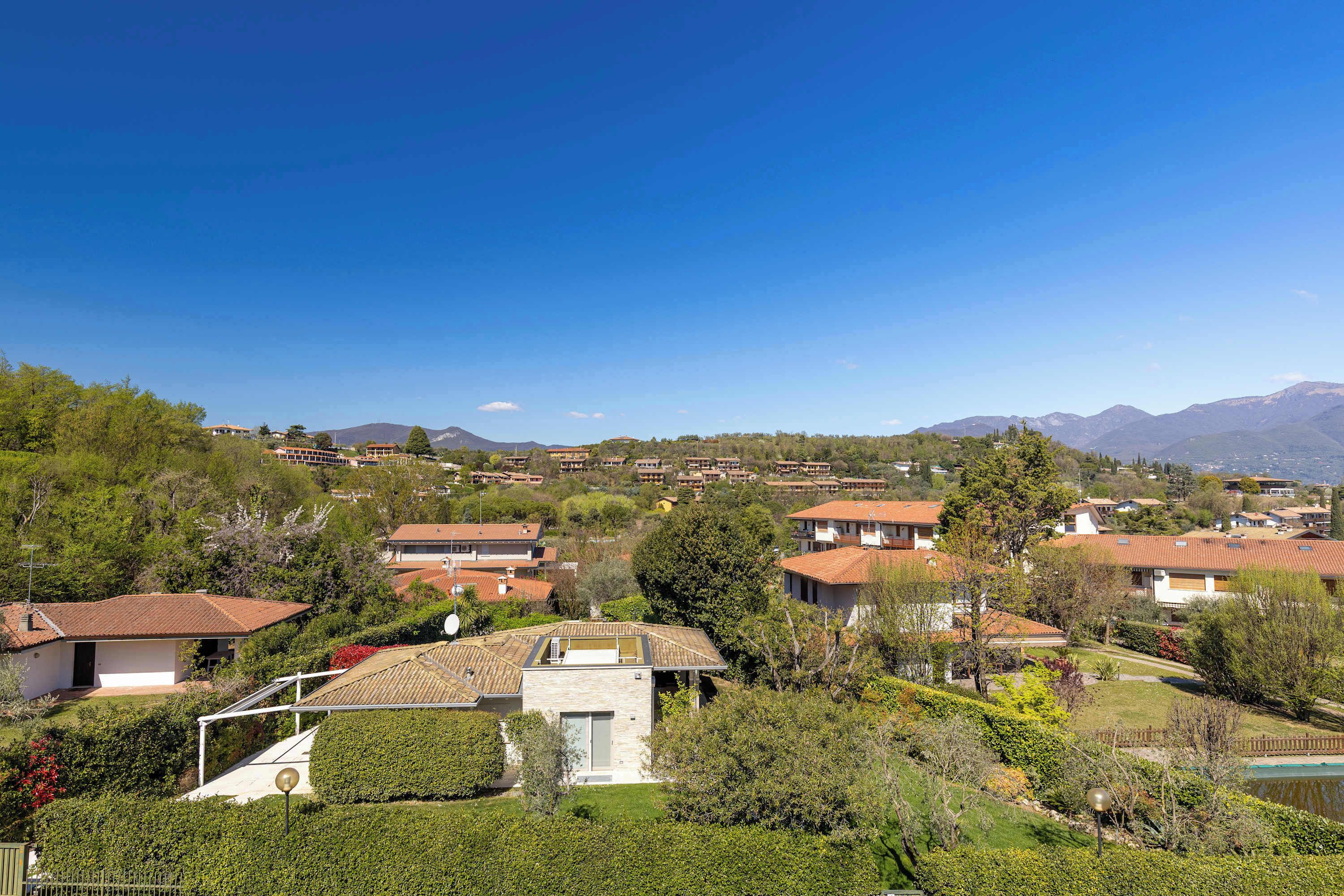 A residential area with houses, a clear blue sky, and mountains in the background.