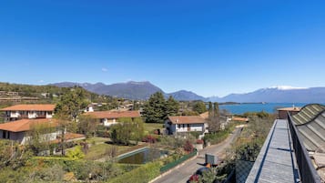 A residential area with houses, a road, and a lake with mountains in the background.