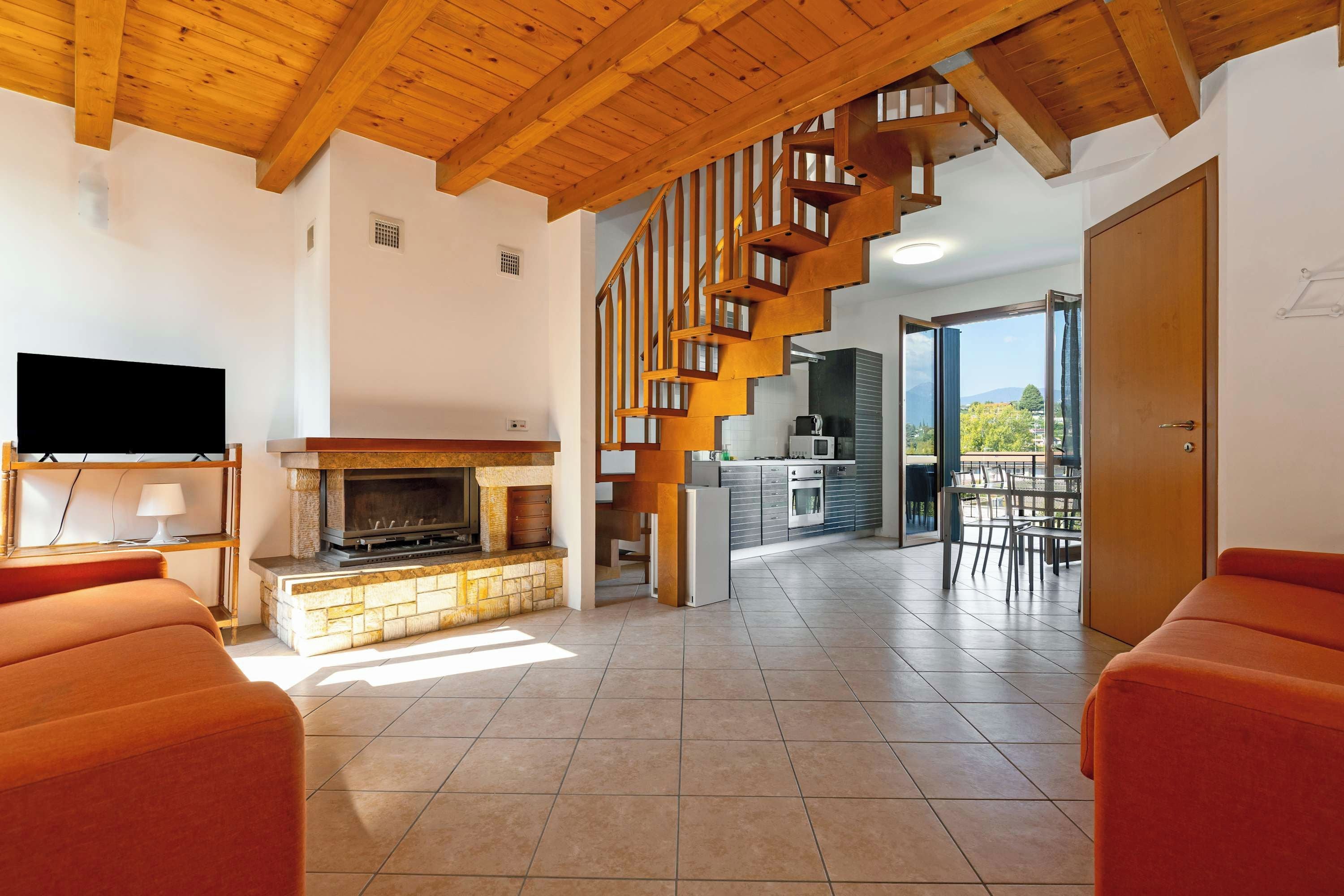 Un salon moderne avec une cheminée, un téléviseur et un escalier menant à un balcon.