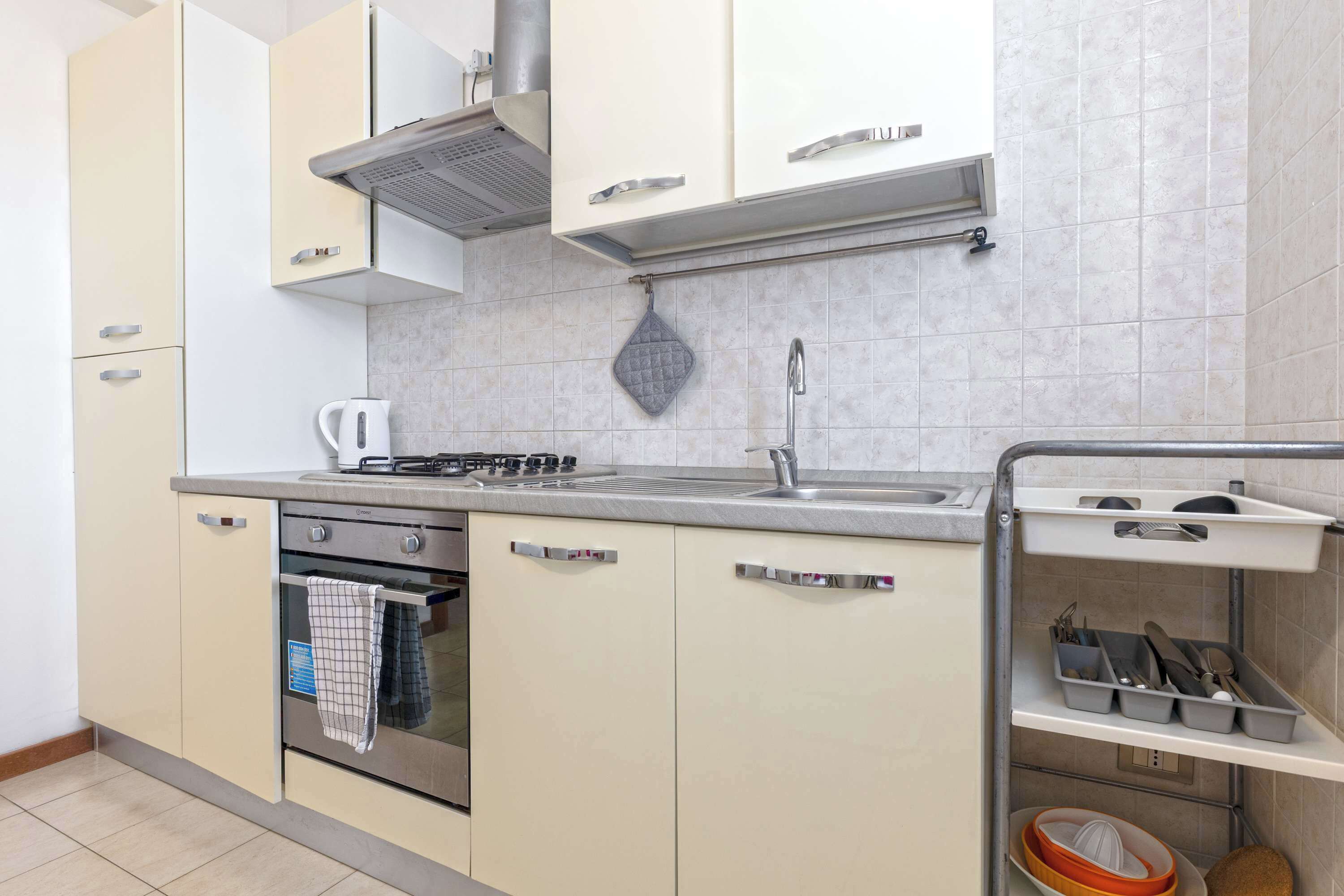A kitchen with a stove, oven, sink, and a utensil holder.