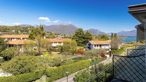A residential area with houses, a small pond, and mountains in the background. - App.14- Le Terrazze del Garda Immobili e Soluzioni (Manerba del Garda)