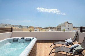 Terraza en la azotea con hidromasaje, sillones de descanso y vistas a la ciudad.