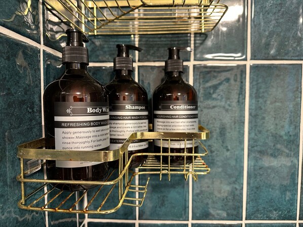 Un estante de baño con tres botellas de jabón corporal, champú y acondicionador.