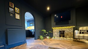 A modern living room with a stone fireplace, a flat-screen TV mounted on the wall, and a cozy seating area with a patterned rug and a sofa.