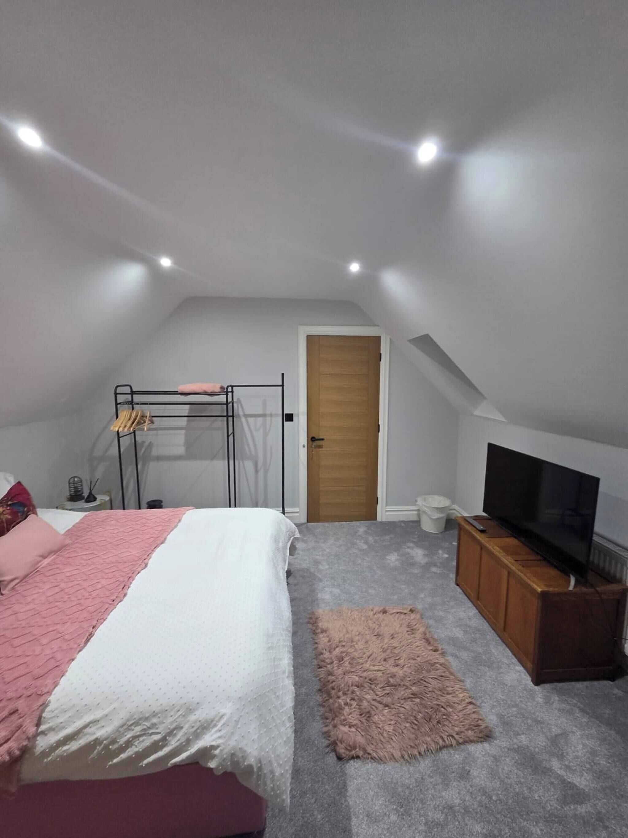 A bedroom with a bunk bed, a television, a wooden cabinet, and a door.