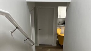Una escalera que lleva a un cuarto con una cocina visible al fondo.