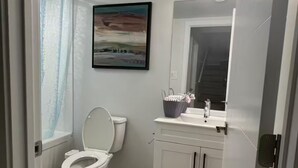 Un baño con inodoro, lavabo, armario y un cuadro en la pared.