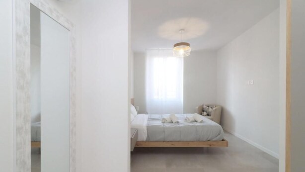 A bedroom with a bed, a bedside table, a hanging light fixture, and a window with curtains. - Benedetta Suite in Florence (Florence)