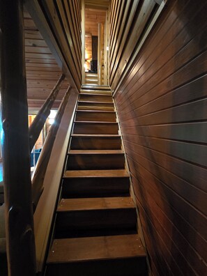A wooden staircase with metal railings, leading to a higher floor.