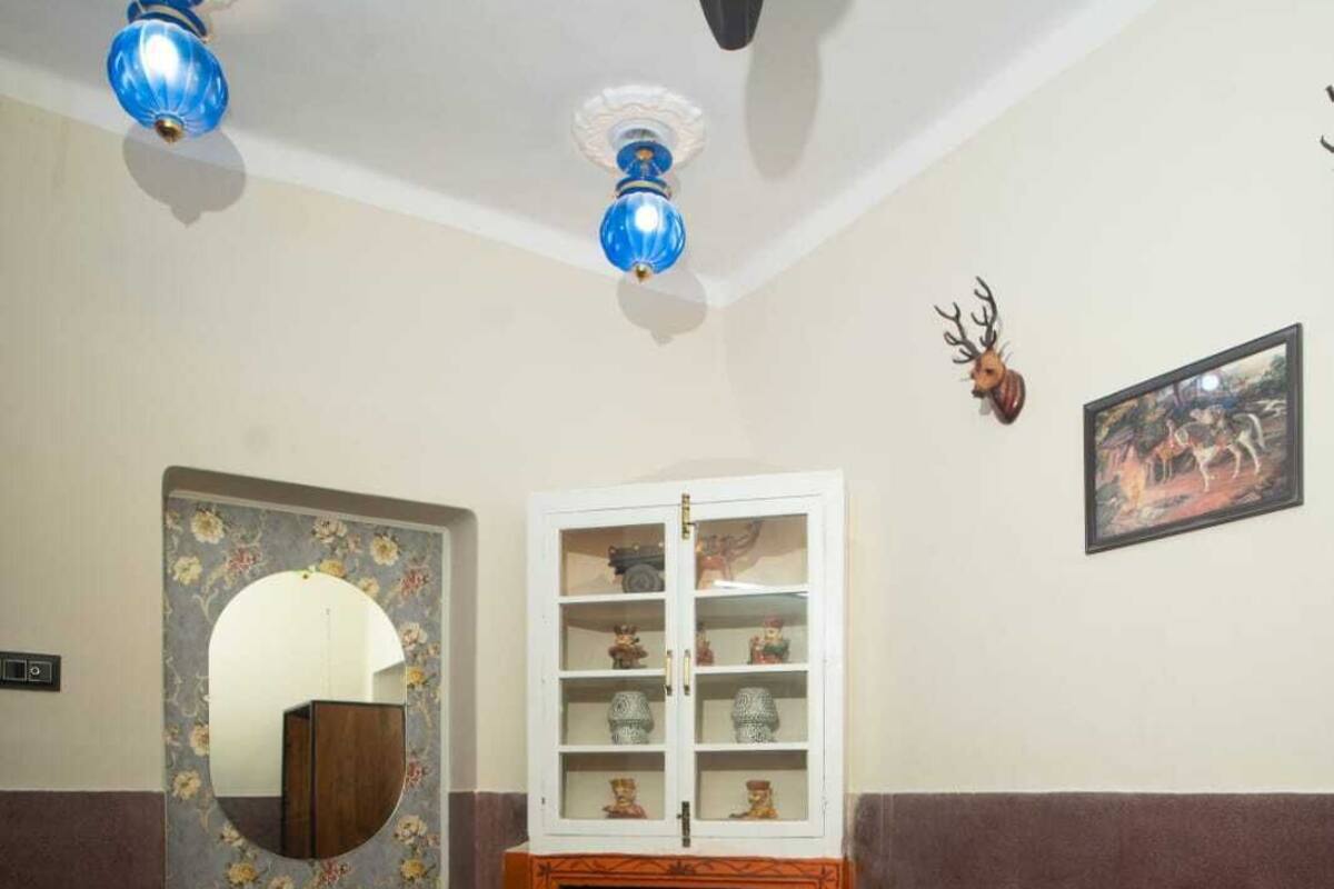 Un salon avec deux canapés marron, une table basse en verre, une cheminée, un miroir décoratif et un meuble avec des portes en verre.