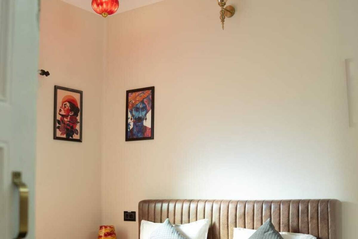 Une chambre à coucher avec un lit, des oreillers, un ventilateur de plafond et des œuvres d’art murales.