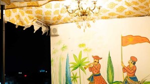 Una stanza con pavimento a scacchi, un tavolo e quattro sedie. Sul muro è presente un affresco che raffigura due figure, una delle quali tiene una bandiera.