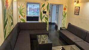 Un'area lounge moderna con divani scuri, un tavolino in vetro e decorazioni alle pareti.