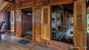 A traditional wooden house with open doors leading to a room with a bed and a green mat on the floor. - Romantic Joglo Villa Near Lovina Beach & Center (Buleleng)