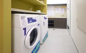 Ein Waschraum mit zwei Waschmaschinen, einem Waschbecken und einer Arbeitsplatte mit Unterlagen.