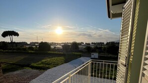 Uma varanda com vista para o pôr do sol sobre uma paisagem com árvores e um rio.