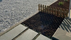 Uma área de estacionamento de cascalho com cerca de madeira e um edifício com fachada de tijolos.