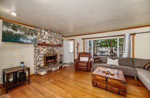 A living room with a stone fireplace, a leather armchair, a sofa, and a wooden coffee table. - The Blue Bear Cabin Lake Tahoe Family Getaway 2 Bedroom Home (South Lake Tahoe)