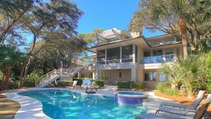 Kaksikerroksinen talo, jossa on uima-allas, poreallas ja katettu terassi, jossa on aurinkotuoleja.