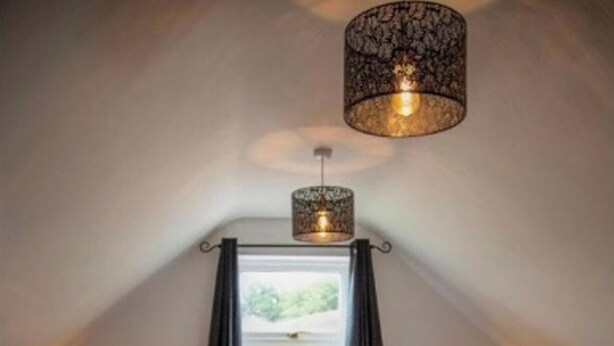 A bedroom with a large bed, two bedside tables with lamps, a window with curtains, and a hanging light fixture. - 4 Bed House Sleeps 10 - Pets, Parking, Games Room (Filey)