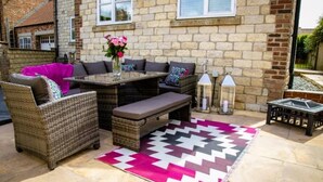 An outdoor patio with wicker furniture, a table, and a decorative rug. - 4 Bed House Sleeps 10 - Pets, Parking, Games Room (Filey)