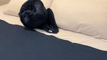 A bed with a dark blue bedspread and pillows, a dark blue blanket, and a dark blue pillow.