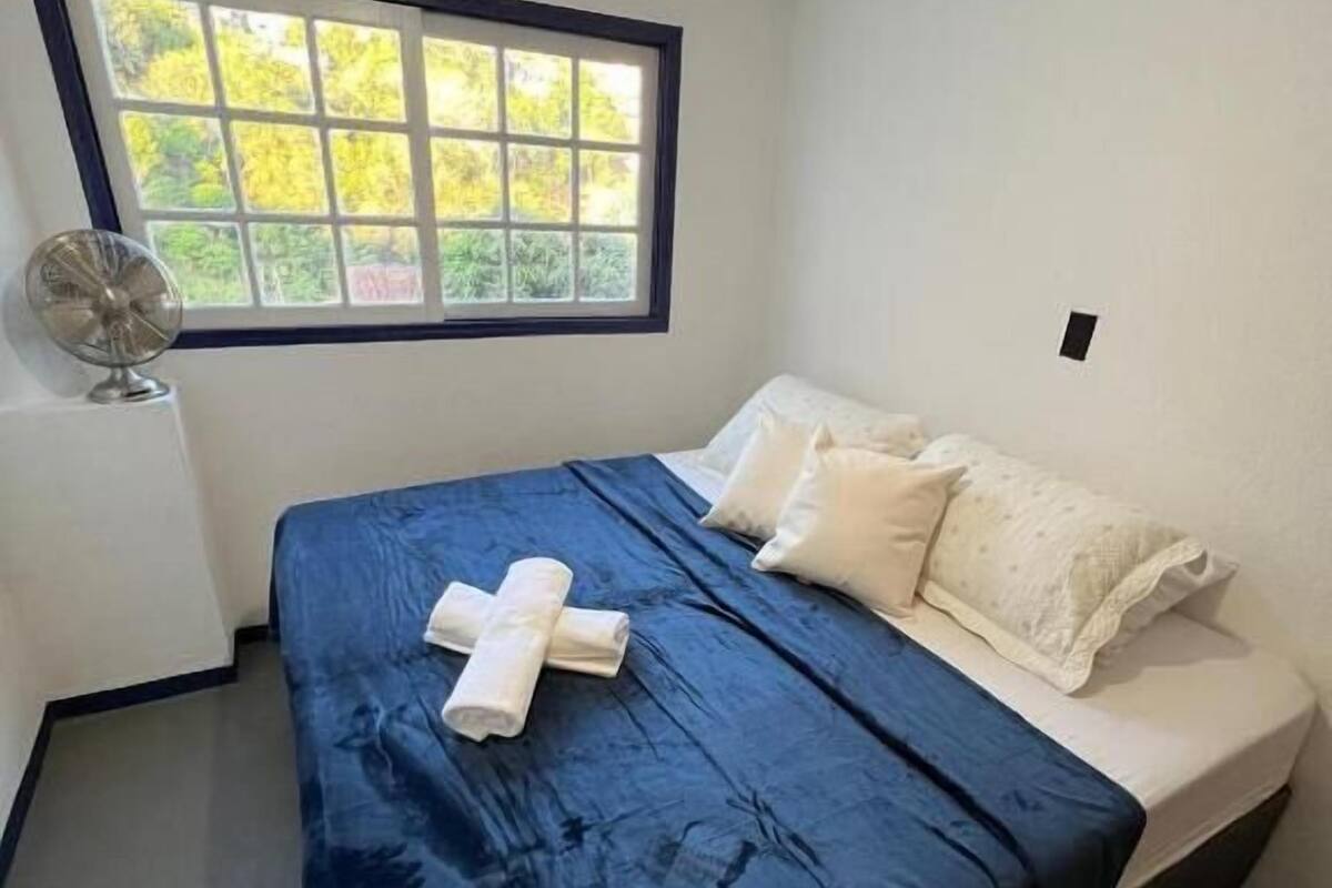A bedroom with a bed, a window, and a fan.