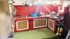 Una cocina con encimera roja, armarios de madera y diversos electrodomésticos.