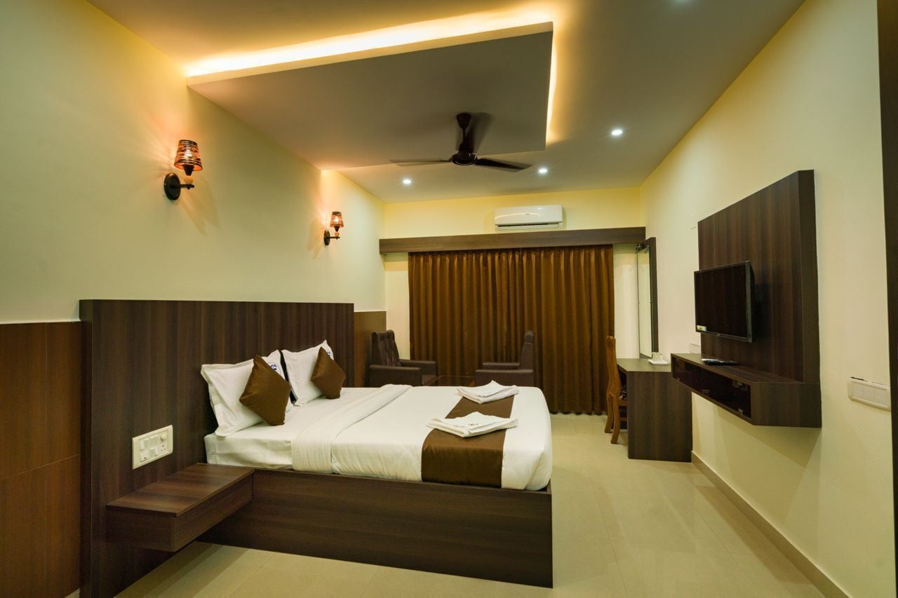 A modern hotel room with a large bed, a flat-screen TV, a ceiling fan, and a seating area with a view of the outdoors.