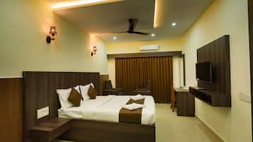 A modern hotel room with a large bed, a flat-screen TV, a ceiling fan, and a seating area with a view of the outdoors.