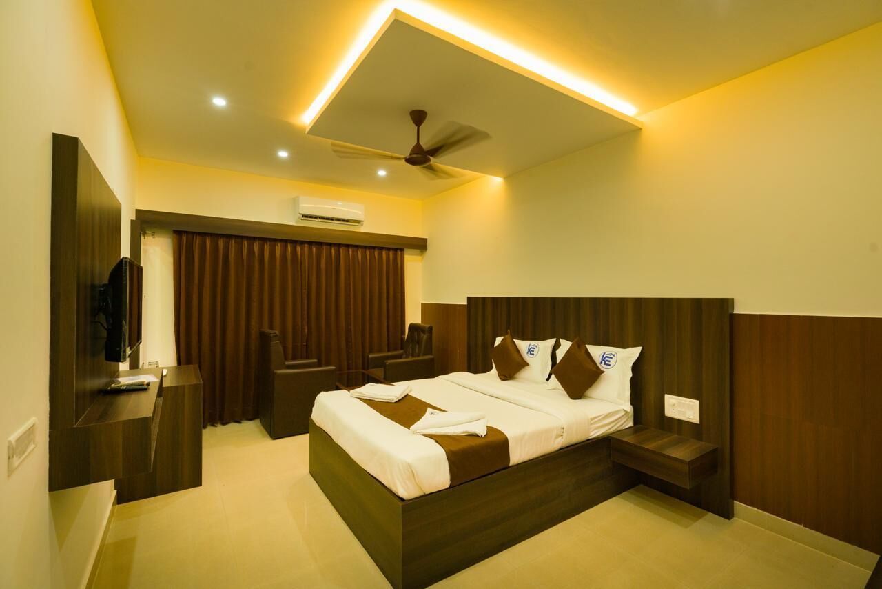 A modern hotel room with a large bed, a ceiling fan, and a TV on a wooden stand.