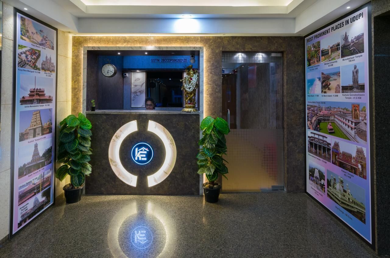 Zona de recepción de un hotel con diseño moderno, que incluye un mostrador de recepción, un reloj y carteles informativos en las paredes.