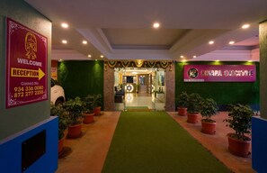 Zona de recepción de un hotel, con un mostrador de recepción, un cartel de bienvenida y una señalización para la suite ejecutiva.