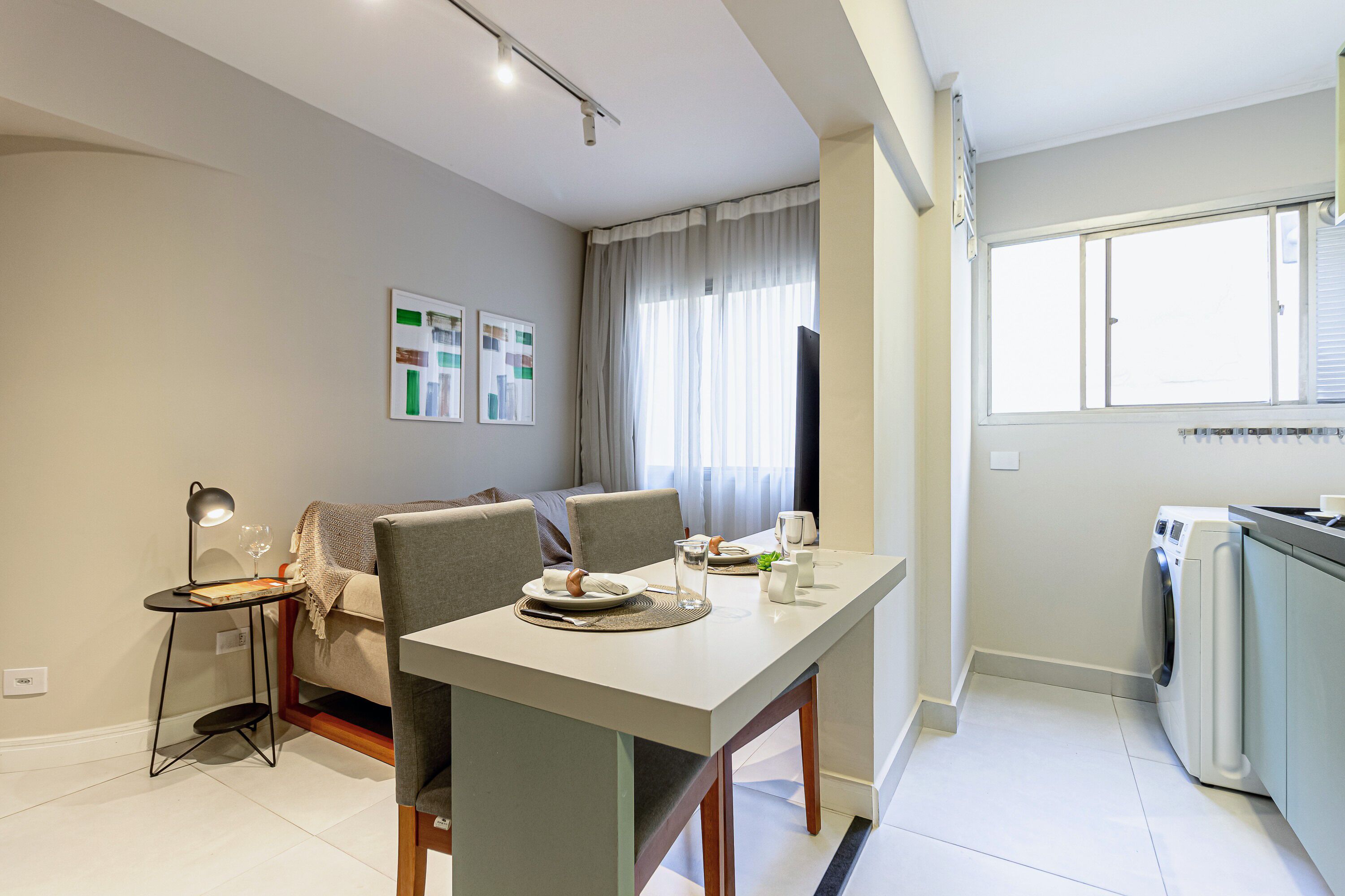 A modern living room with a dining table, a sofa, and a kitchen area with a washing machine.