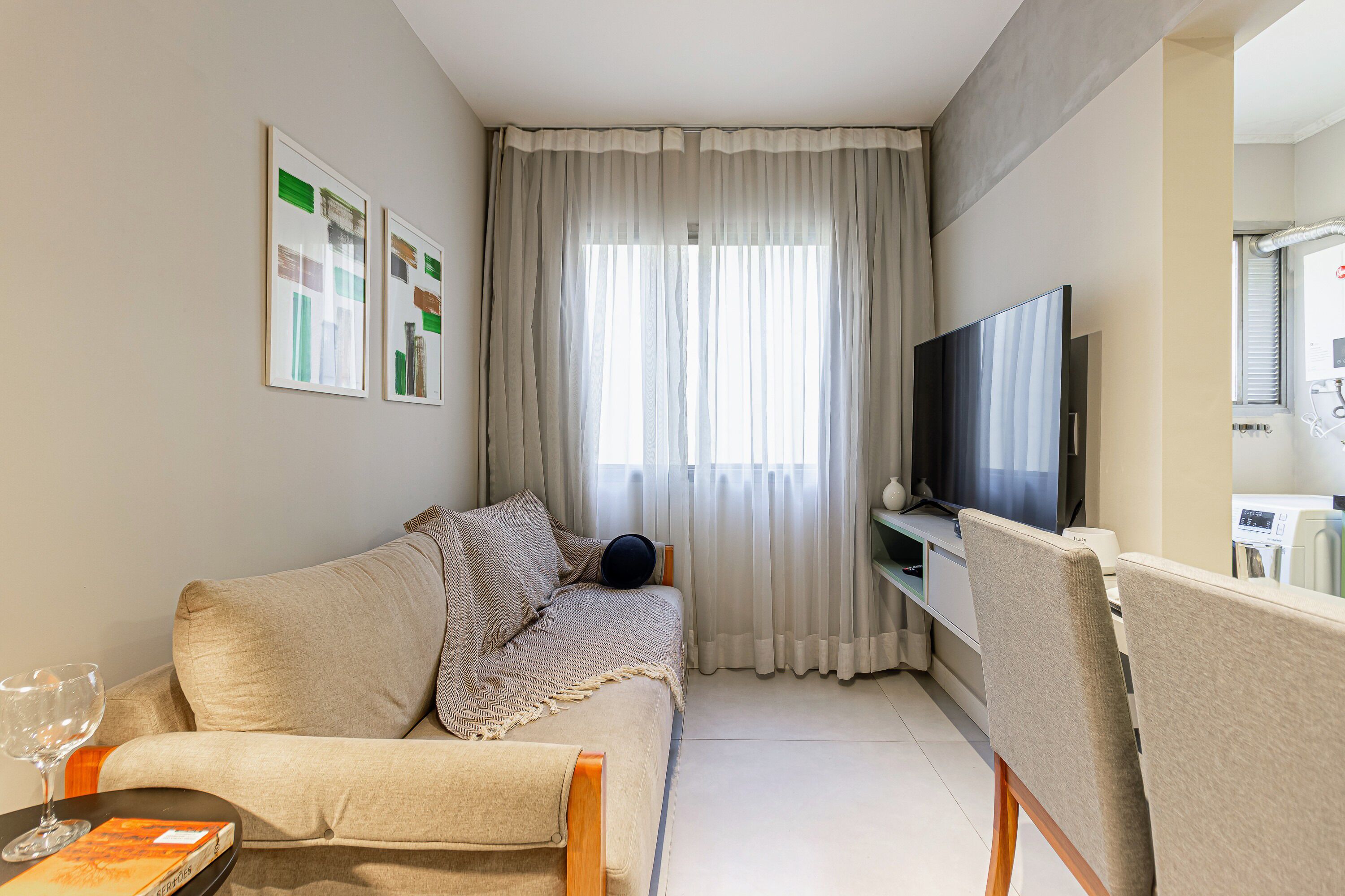 Una sala de estar con un sofá, televisión y una mesita de centro con un libro y un vaso.