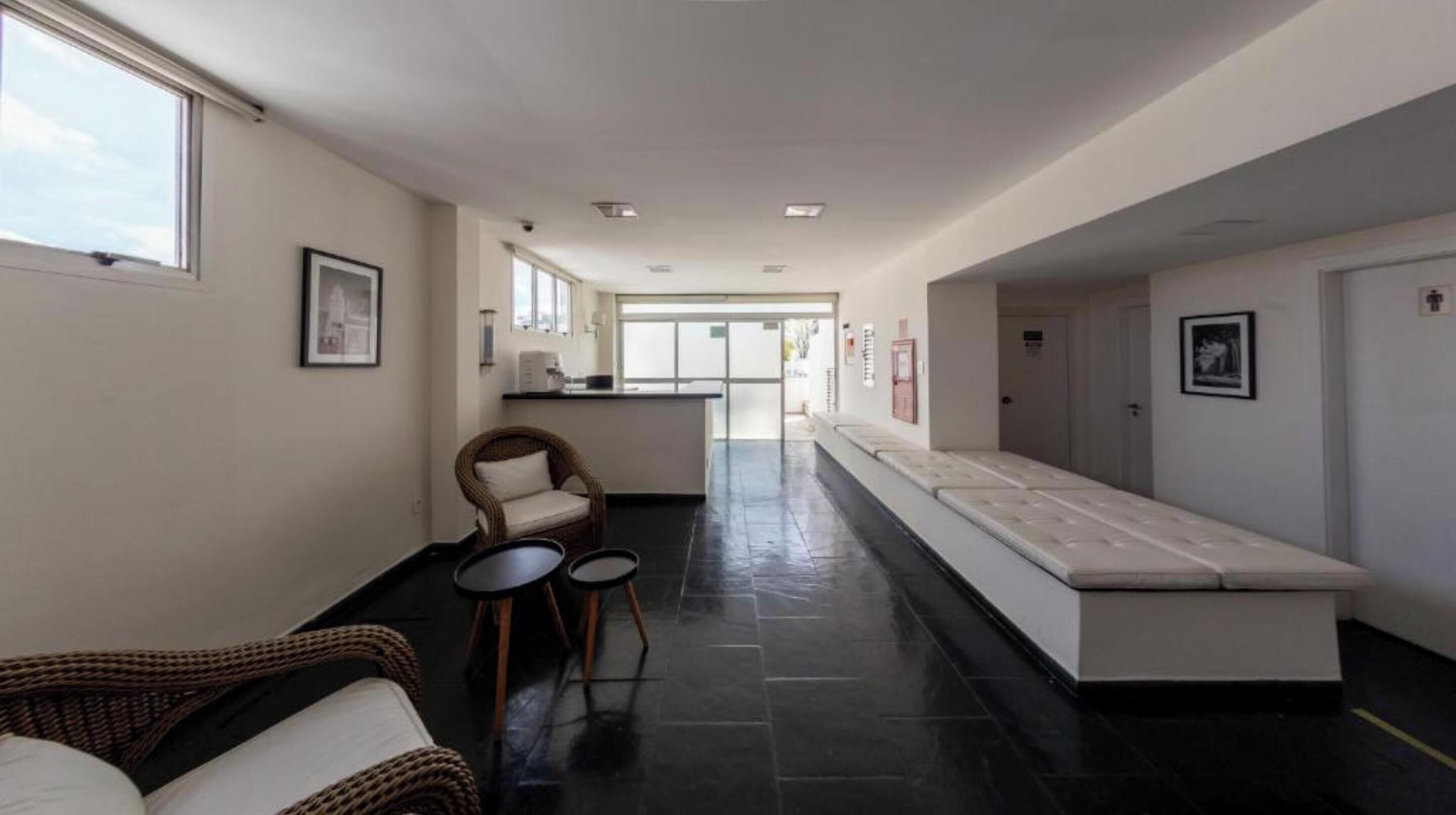 A hallway with a seating area, a reception desk, and a long bench.