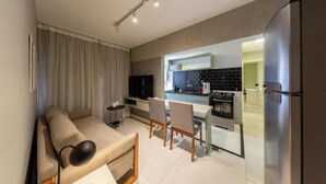 Ein modernes Wohnzimmer mit Sofa, Fernseher und einem Essbereich mit Stühlen und Tisch.