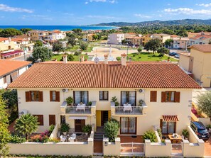 A two-story building with a tiled roof, a balcony, and a view of the sea. - Capo Comino 1 - Two Bedroom Apartment, Sleeps 5 (La Caletta)