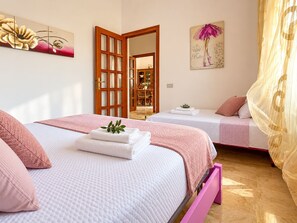 Une chambre d’hôtel avec deux lits, une porte en bois, un miroir et un tableau au mur.