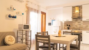 Una cocina moderna con armarios blancos, un microondas y un comedor con mesa y sillas.