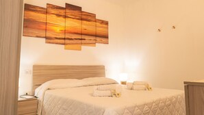 Una habitación de hotel con una cama, una mesita de noche, una lámpara y una obra de arte colgada en la pared.