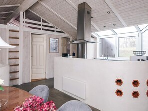 A modern kitchen with a central island, a built-in stove, and a large window providing natural light. - 4 Star Holiday Home in Ebeltoft (Ebeltoft)