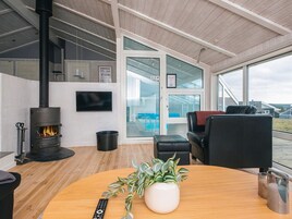 A modern living room with a wood-burning stove, a television, and a large window overlooking a pool.