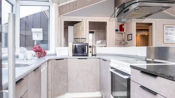 Una cocina moderna con horno empotrado, microondas y campana extractora de acero inoxidable.