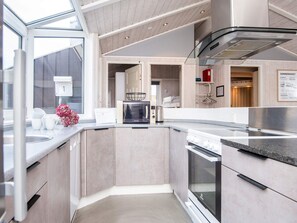 A modern kitchen with a built-in oven, microwave, and a stainless steel range hood. - 4 Star Holiday Home in Ebeltoft (Ebeltoft)