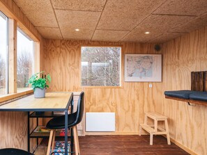 A room with wooden walls, a window, a map on the wall, a table with a plant, a chair, a laptop, and a small stool. - 4 Star Holiday Home in Ebeltoft (Ebeltoft)