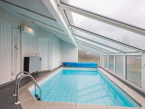 An indoor swimming pool with a skylight ceiling, a blue pool cover, and a water heater. - 4 Star Holiday Home in Ebeltoft (Ebeltoft)