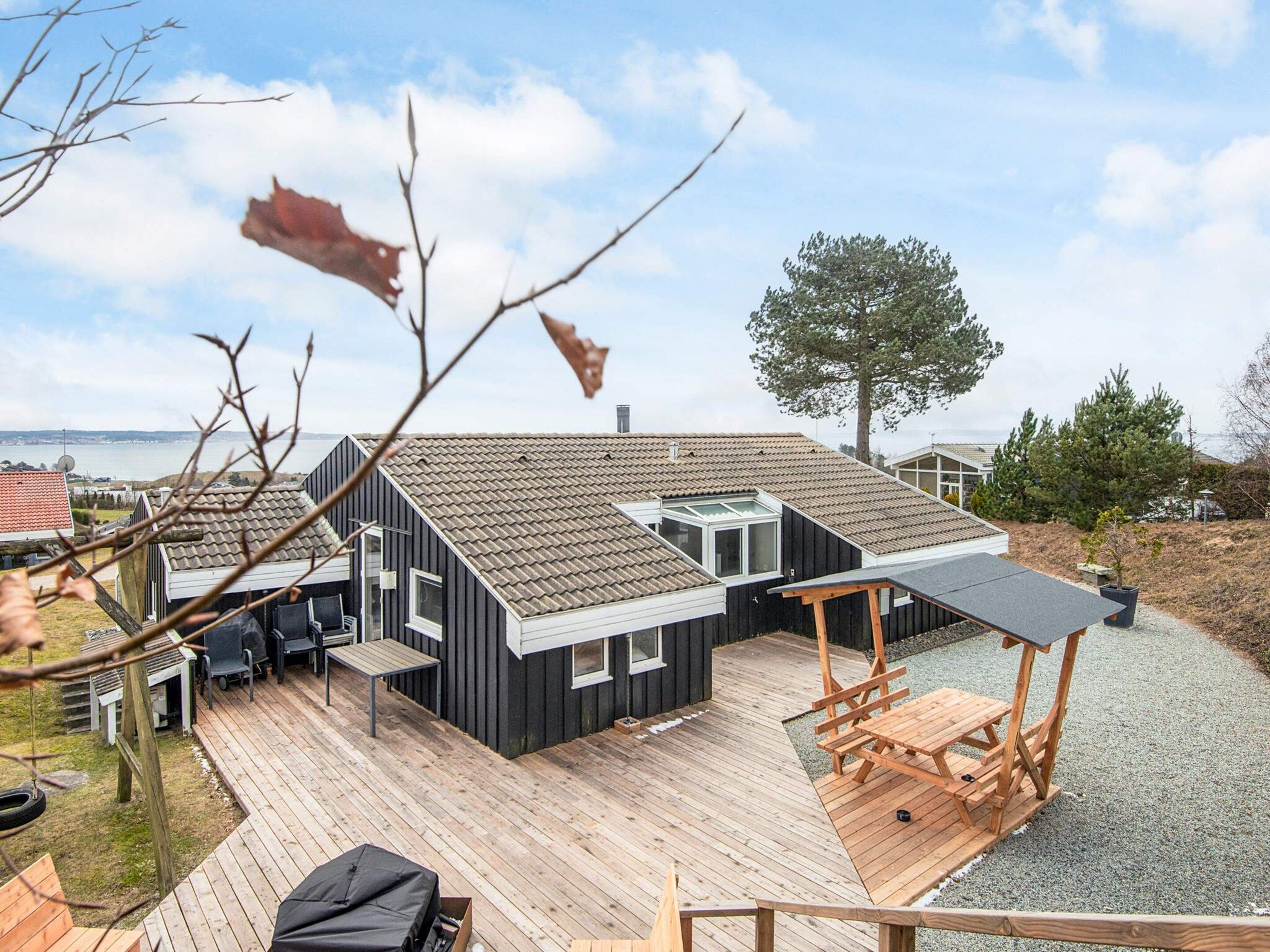 A modern house with a deck, a covered outdoor seating area, and a view of the sea.